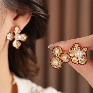 Details von Vintage Goldene Blumenohrringe mit Perle auf einem warmen Hintergrund