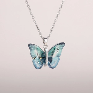 Detail of butterfly pendant necklace with blue green resin wings and silver chain