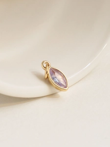 Macro shot of an 18K gold-plated teardrop pendant featuring a clear purple zircon stone