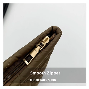 Detailed close-up of smooth gold metal zipper on brown quilted fabric makeup bag