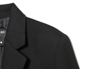 Close-up of lapel and shoulder tailoring on a premium black textured fabric blazer