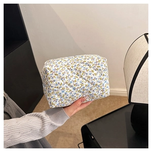 Close-up of a floral cotton makeup bag with blue flowers and quilted diamond texture