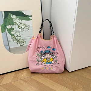 Detail shot of a pink canvas tote bag featuring delicate sheep and floral embroidery