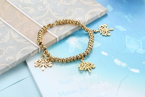 Détail d'un bracelet doré à billes avec breloques arbre de vie et fermoir mousqueton