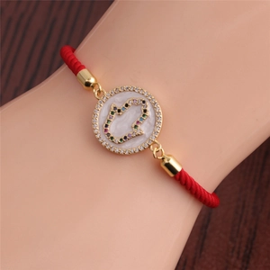 Detail of red braided Hamsa hand bracelet with colorful cubic zirconia and gold plating