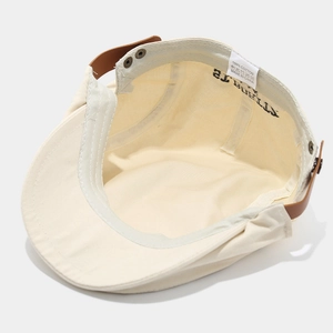 Detail view of cotton flat cap interior with brown leather strap and metal rivet buckle