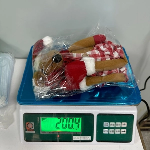 Peluche natalizio in abito scozzese su una bilancia digitale con peso di 200g