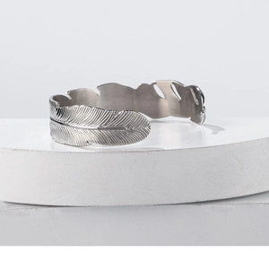 Detailed close-up of adjustable silver feather bangle with intricate engraved textures
