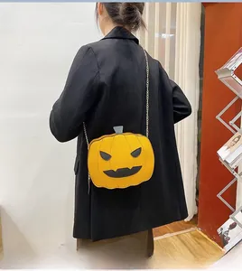 Chic pumpkin crossbody bag with black face detail and silver chain on a model back