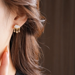 Detailed close-up of cloud-shaped shell earrings with sparkling zircon water drops