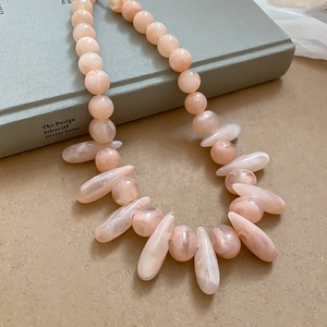 Detailed close-up of bohemian pink beaded necklace with resin textures on vintage books