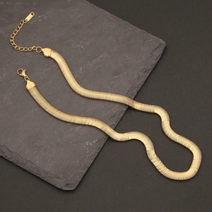 Close-up of golden snake chain necklace with lobster clasp on dark stone background