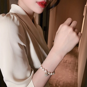 Elegante parelarmband met gouden schelphanger aan de pols voor dames mode