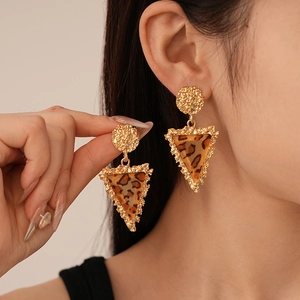 Detail of vintage leopard print resin earrings with golden geometric inverted triangle frame