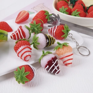Lifelike artificial strawberry keychains and pendants in a fresh aesthetic tea setting