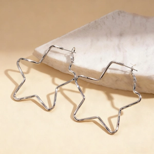 Close-up of minimalist silver star-shaped metal earrings on a white marble surface