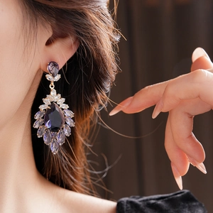 Détails de boucles d'oreilles vintage avec zircons violets portées par le mannequin