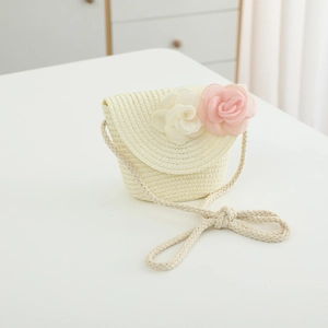 Detail of child straw crossbody bag with delicate pink and white floral ornaments
