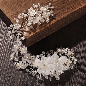 Detailed close-up of bridal hair comb with silver wire, pearls, and crystal flowers