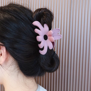 Primer plano de una pinza para el pelo con flor rosa mate usada por una modelo