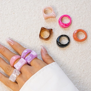 Close-up of marble pattern acrylic rings in square and round shapes on hand and table