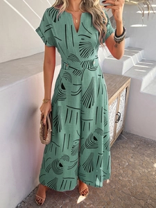 Detail view of a green V-neck jumpsuit featuring black geometric patterns and waist buttons