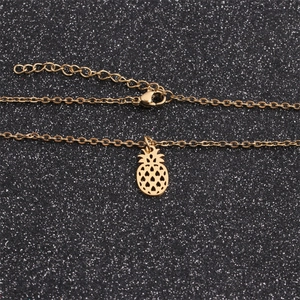 Detailed view of polished gold pineapple pendant with intricate laser cutouts on a chain