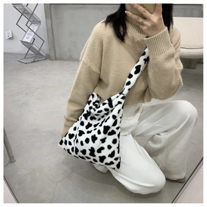Detail of soft faux fur crossbody bag with black and white cow print texture for women