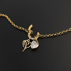 Detailed macro view of gold titanium steel necklace featuring heart and sparkling crystal charms