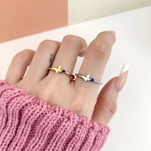 Close-up of gold and silver butterfly rings with blue gemstones on a model's hand