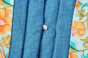 Makro-Detail der Baumwolljacke im Denim-Look mit Blumendruck und weißem Knopf