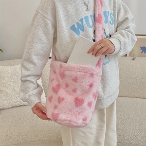 Detail of pink plush heart pattern bucket bag being used in a cozy home setting