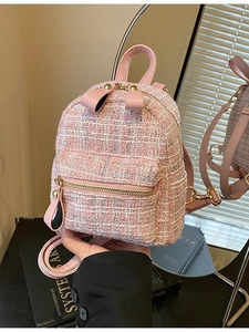 Pink tweed mini backpack with gold zippers and bow detail shown in a lifestyle mirror shot