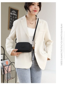 Modern black nylon crossbody bag worn by a model in a casual business setting