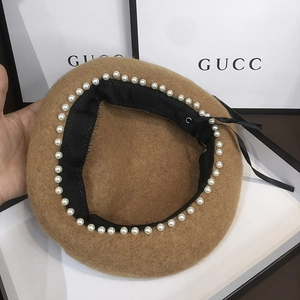 Detail of wool octagonal beret featuring elegant white pearls and a black satin bow