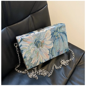 Detail of floral tapestry fabric and silver chain on a vintage square box clutch bag