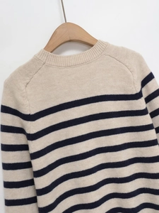 Detailed view of the round neckline and striped knit texture on an oatmeal sweater