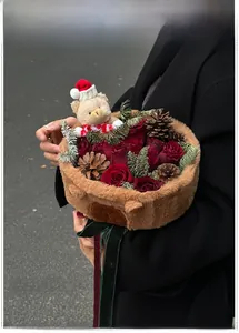 Close-up of Christmas flower bouquet with red roses, pine cones, and a plush bear toy