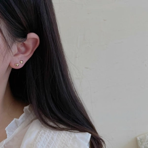 Close-up of heart-shaped gold stud earrings worn by a model for a minimalist jewelry look
