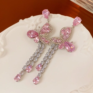 Macro detail of silver needle earrings with pink zircon butterfly and long tassels