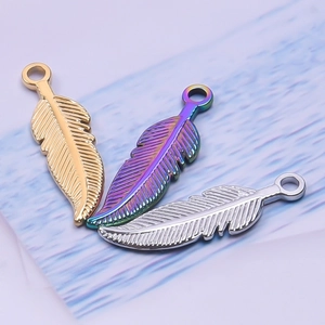 Detailed view of feather pendants in gold, silver, and rainbow finishes on blue texture