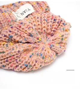 Macro view of multi-color knit beanie stitching with a fabric woven brand label