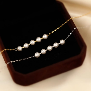 Minimalist gold and silver titanium necklaces with five pearls on a silk background