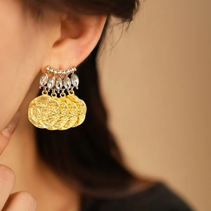 Detail of vintage French gold earrings with crystal inlay and coin pendants on a model