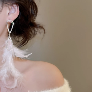 Detail von eleganten weißen Feder-Ohrringen mit funkelndem Diamantbesatz getragen am Model