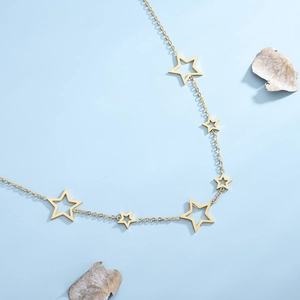 Elegant gold necklace with hollow star pendants on a light blue background decoration