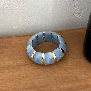 Détail du bracelet élastique en résine marbrée bleu ciel et segments dorés