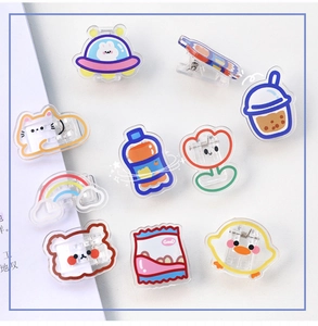 Flat lay of nine cute acrylic clips featuring cartoon cats, bears, and food designs