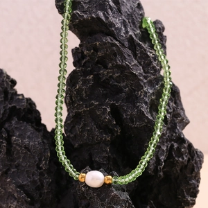 Detail of green faceted beads and a white freshwater pearl on a beaded necklace