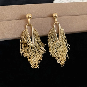 Detailed macro view of gold tassel earrings with geometric triangle frames on a display